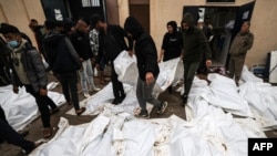 2023年12月25日,在加沙地带南部代尔巴拉赫的阿克萨医院举行集体葬礼之前,医务人员和志愿者摆放的在以色列袭击马加齐难民营时丧生人员的尸体。(法新社照片)