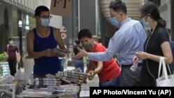 周五(6月18日),路人在香港街头购买《苹果日报》。该报周四被警方突袭,并有5名高管和记者被拘捕。(美联社照片)