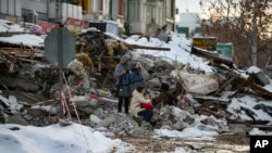 土耳其城市马拉蒂亚的地震灾民坐在房屋废墟上。 (2023年2月7日)