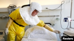 2014年10月15日,瑞士巴塞尔医院的一名感染控制护士穿着防护服向媒体介绍埃博拉病人使用的隔离病房。