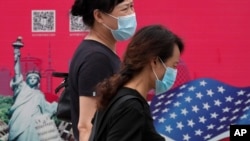 北京街头行人走过有着美国国旗和纽约自由女神画像的广告牌。（2020年8月6日）