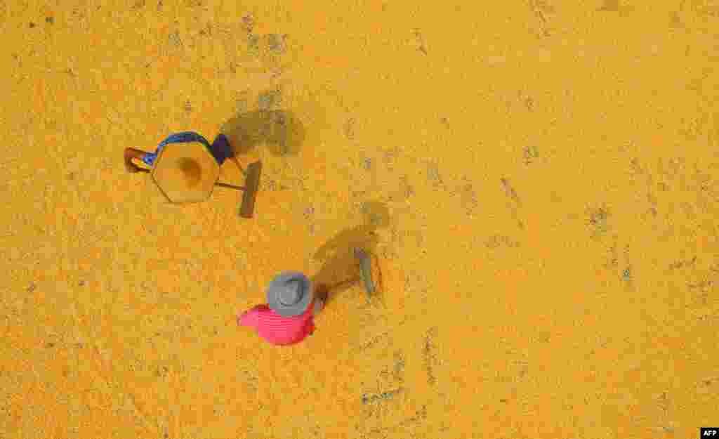 中国山东省临沂市郯城县,2018年8月30日,两位农民在收获季节晒玉米。中国玉米不能自给自足,需要进口。对美国玉米增加关税会抬高中国市场上的玉米价格,而不少玉米用于猪饲料,所以也会抬高猪肉价格。由美国国会成立的美中经济与安全审查委员会的报告说,在中美贸易战阴霾下,6月份美国对中国农产品出口与去年同比下跌34.4%。