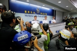 香港警务处长卢伟聪和其他香港高级警官在2019年6月13日召开的记者会上面对为谴责警察使用暴力应对民众示威而头戴保护性头盔的记者们。