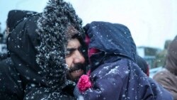 一位移民在白俄罗斯-波兰边境关卡附近的一处物资中心外抱着孩子在雪中等待分发下来的食物。(2021年11月23日)