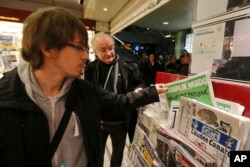 在法国西部的雷恩市,一名男士在报刊亭拿起一份《查理周刊》。(2015年1月14日)