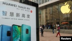 在中国上海的Apple商店外面,顾客排队购买新的iPhone XR手机,附近有华为Mate 20系列产品的广告。(2018年10月26日)