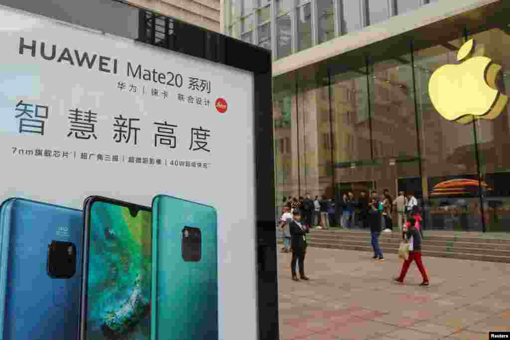2018年10月26日在中国上海的Apple商店外面，顾客排队购买新的iPhone XR手机，附近有华为Mate 20系列产品的广告。华为使用竞争对手苹果的手机发推后，有网民说：&ldquo;连华为员工都觉得iPhone比较好用&rdquo; 。