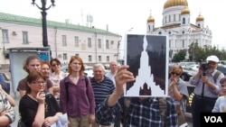 导游帕维尔手举苏维埃大厦和列宁像方案,后面是苏联解体后新建的救世主大教堂。(美国之音白桦拍摄)