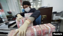 中国江苏省南通市一家银行的职员戴着口罩整理人民币钞票。(2020年1月30日)