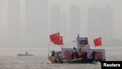 12月26日在湖北武汉,打着中国国旗、展示已故中共领导人毛泽东巨幅画像的船只引领着人们进行冬泳