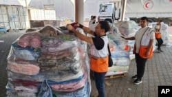 资料照:2023年10月23日星期一,联合国和红新月会工作人员在加沙地带代尔巴拉赫近东救济工程处的仓库准备分发给巴勒斯坦人的援助物资。(美联社)