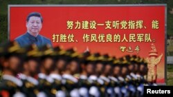 资料照:解放军士兵列队在有着中国领导人习近平画像的宣传牌前走过。(2015年8月22日)