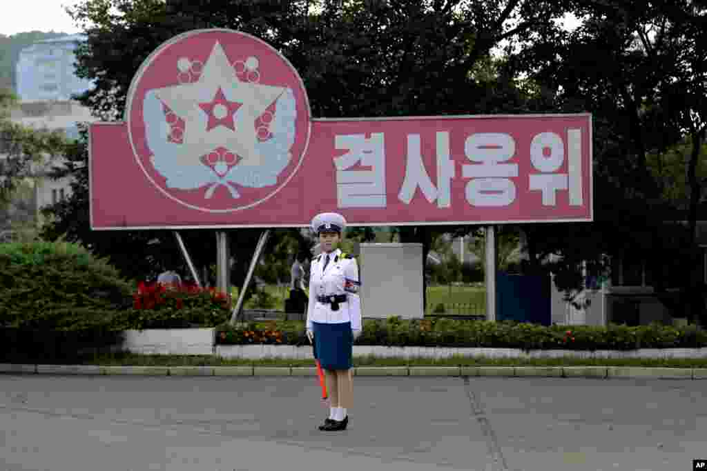 平壤一名交通女警站在十字路口,她身后的标语牌上写着“誓死保卫”(2017年7月29日)。