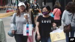 为防疫戴口罩的台湾民众走过台北的购物街区。(2020年10月29日)