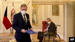 坐在有机玻璃隔间的捷克总统米洛斯·泽曼任命菲亚拉(左)为总理。