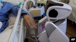 2020年4月8日意大利瓦雷泽市接受治疗的冠状病毒患者与机器人互动。