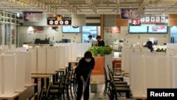 香港为控制新冠病毒感染而暂停晚市服务后,一名餐厅职员在空荡荡的美食广场擦拭地板(2022 年 1 月 11 日)