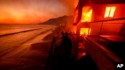 资料照片:洛杉矶马利布地区的消防员正在努力扑救一栋燃烧的海滨建筑。(2025年1月8日)