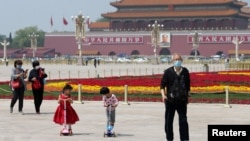 戴着口罩的北京市民在天安门广场为五一劳动节建起的花坛旁散步。(2020年4月29日)