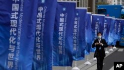 资料照:一名男子走过上海街头插满的宣传旗帜:“中国式现代化与世界”。 (2023年4月21日)