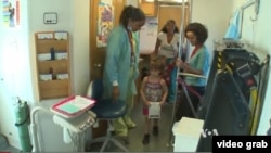 Một bé gái được mẹ đưa đến trạm nha khoa lưu động để khám răng