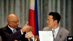 菲律宾众议员比亚松(左)和日本代表团团长、在野的日本创新党领袖中田宏在签署一项推动海上法治的非正式协议后握手。