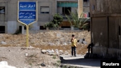 2016年9月19日,叙利亚中心城市霍姆斯瓦尔区的入口处站着一个男孩。