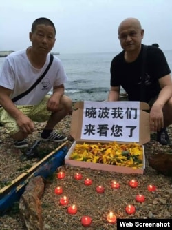 姜建军(左)、王承刚在大连老虎滩海边祭奠两天前葬于附近海域的刘晓波。(2017年7月17日 推特图片)