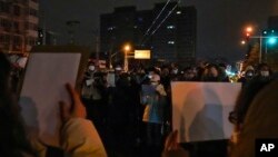 中国多个城市的民众2022年11月27日举起白纸抗议当局严厉的防疫封控措施。(美联社)