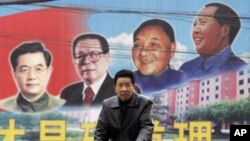 有人骑自行车路过山西的一块带有邓小平等领导人画像的公告牌(2009年2月)