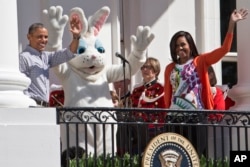 巴拉克·奥巴马总统和夫人米歇尔·奥巴马与复活节兔子在一起向参加白宫复活节彩蛋的孩子们挥手致意。(2015年4月6日)