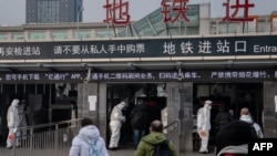 北京地铁站保安人员身穿防护服检测地铁乘客的体温。(2020年1月27日)