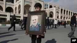 A boy carries a portrait of Iranian Revolutionary Guard Gen. Qassem Soleimani before Friday prayers in Tehran, Jan. 3, 2020. Iran has vowed "harsh retaliation" for the U.S. airstrike near Baghdad's airport that killed Tehran's top general.