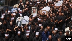 2024 年 7 月 28 日,在以色列吞并的戈兰高地德鲁兹镇举行的大规模葬礼上,哀悼者抬着棺材和一天前在火箭袭击中丧生的人的照片。(法新社)