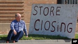 盐湖城,“欧洲珍宝”古董店店主埃文斯坐在他的“商店关门”标志旁(2020年5月8日)。