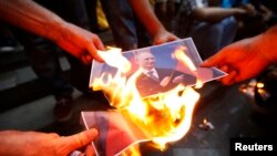 Người biểu tình đốt ảnh chân dung của Tổng thống Nga Vladimir Putin trong cuộc biểu tình ủng hộ Ukraine ở Gruzia.