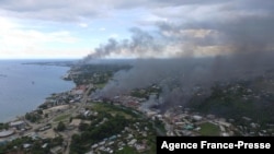 从所罗门群岛首都霍尼亚拉被焚烧的建筑冒出的浓烟。(2021年11月25日)