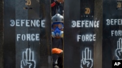 在仰光,抗议者站在防御安全部队的自制屏障的后面。(2021年3月11日)