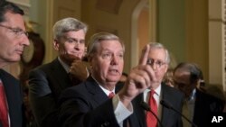 格雷厄姆-卡西迪法案的起草人格雷厄姆参议员发表讲话,他身后有卡西迪参议员和参议院多数党领袖、肯塔基州参议员米奇·麦康奈尔(2017年9月26日)