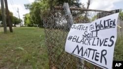 在斯科特被枪杀地点附近的栅栏上挂着一个呼吁执法公正的标语牌(2015年4月8日)