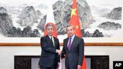 中国官媒新华社发布的照片显示,中国外交部长王毅在北京与到访的日本外务大臣岩屋毅握手(2024年12月25日)。