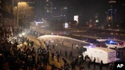 在特拉维夫,以色列警方使用高压水枪驱散封阻公路的示威者。人群抗议总理内塔尼亚胡的司法改革计划。(2023年3月27日)