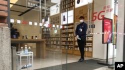 武汉周一解封,一家重新开门的商店的营业员在门口等候顾客。(2020年3月30日)