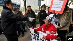 在《南方周末》广州总部外,警察指着一名声援《南方周末》的坐轮椅的抗议男子,随后把他带走。(2013年1月10日)