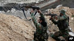 Syrian army soldiers fire their weapons during a battle with rebel fighters at the Ramouseh front line, east of Aleppo, Dec. 5, 2016.