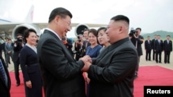 资料照:朝鲜领导人金正恩在平壤国际机场欢迎到访的中国国家主席习近平。(2019年6月21日)