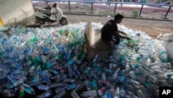 Seorang pekerja India memilah botol-botol plastik bekas sebelum dikirim untuk didaur ulang, di sebuah stasiun kereta pada Hari Lingkungan Dunia, Ahmadabad, India, 5 Juni2018.