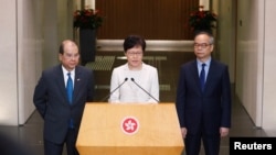 香港特首林郑月娥在记者会上讲话时,署理行政长官张建宗(左)和民政事务局局长刘江华(右)站在她身旁。(2019年9月5日)