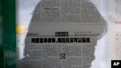 资料照片:一名女子在北京的某处报纸橱窗阅读《环球时报》。该报的文章呼吁忽视美国对中国打压维权律师的批评。(2015年7月14日)