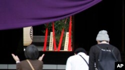 2015年4月21日,人们在一年一度的春季节日参拜位于东京的靖国神社,可以看到背景中心位置是首相安倍晋三供奉的祭品。安倍周二向供奉了已被判刑的二战首领的靖国神社送去宗教祭品,这可能是他不会在出访亚洲和美国前参拜这座有争议的神社的信号。
